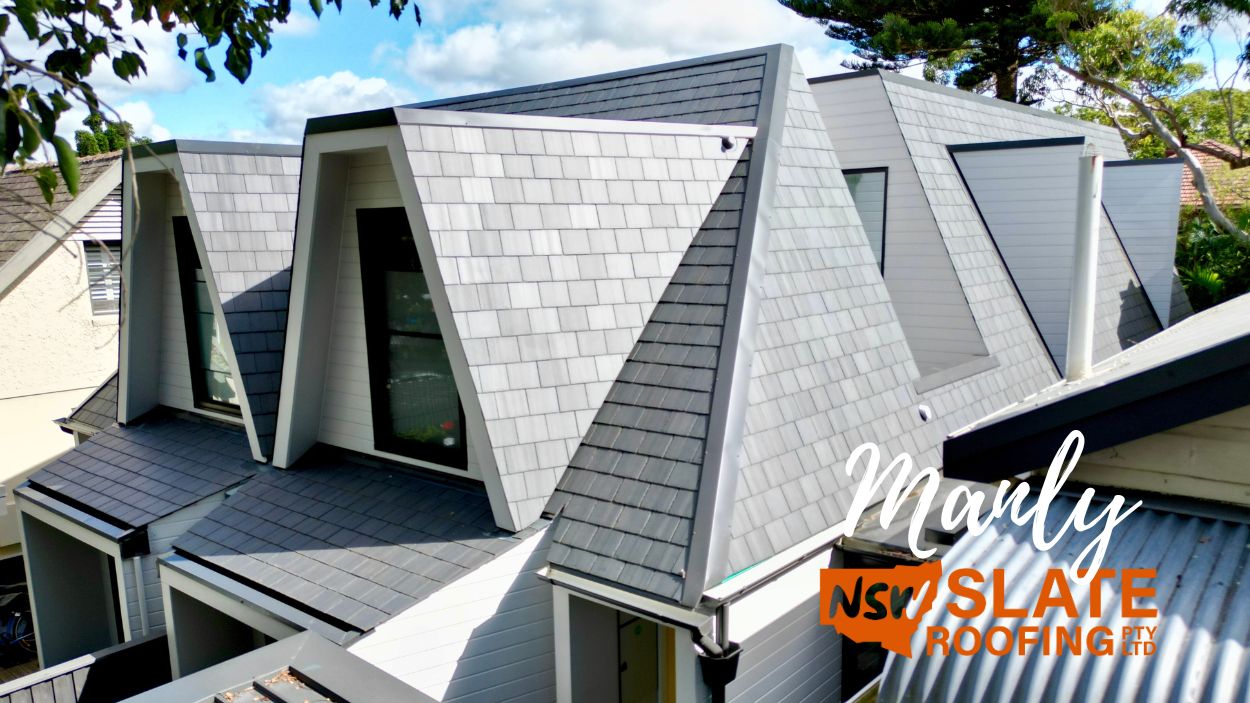 Modern house with steep gabled slate roofs, large windows, surrounded by trees; Heritage Slate Roofing featured.