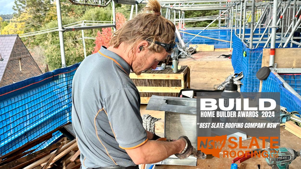allambie-1 NSW Slate Roofing Sydney worker welding metal at a site, beside “Best Slate Roofing Company NSW” award sign.